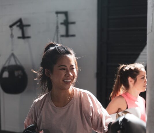 운동과 영양이 현대인의 삶에 미치는 긍정적 영향 woman in pink long sleeve shirt and black pants holding black kettle bell