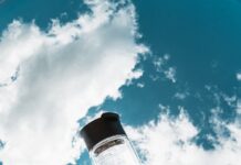 무더위 속 건강하게 여름 나기, 실천해야 할 생활 습관 a hand holding a water bottle in front of a blue sky