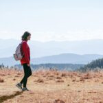 일상 속 걷기 루틴, 건강을 지키는 가장 손쉬운 습관 a man with a backpack walking across a dry grass covered field