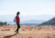 일상 속 걷기 루틴, 건강을 지키는 가장 손쉬운 습관 a man with a backpack walking across a dry grass covered field